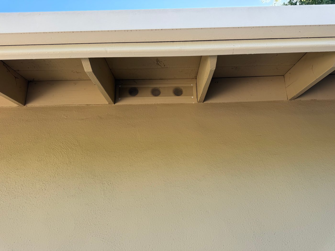 After: ember-resistant eave vent screen installed under the roofline, painted to match the home