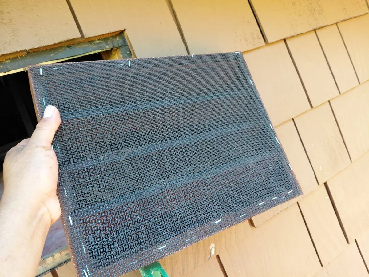 During: a one-eighth-inch stainless steel mesh panel, cut oversize and ready to set behind the existing screen.