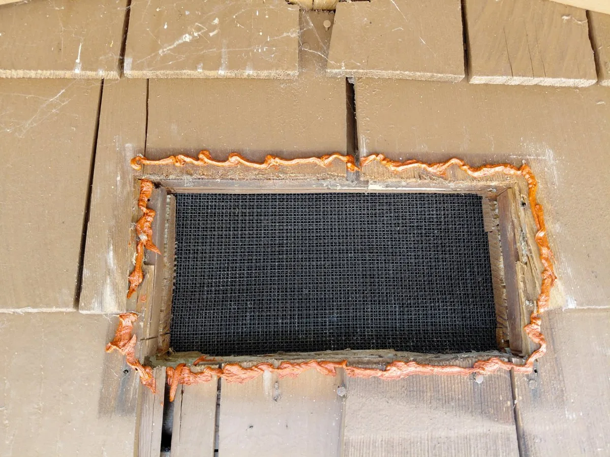 After: fire-blocking foam sealing the wood vent trim to the shake siding on all four sides.