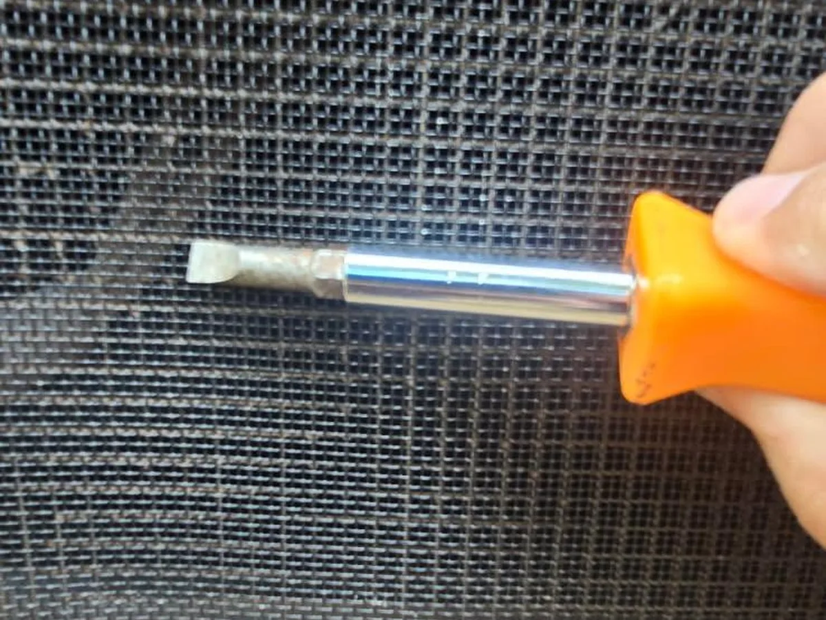 Verification: a screwdriver blade confirms the installed mesh opening is one-eighth inch or finer.