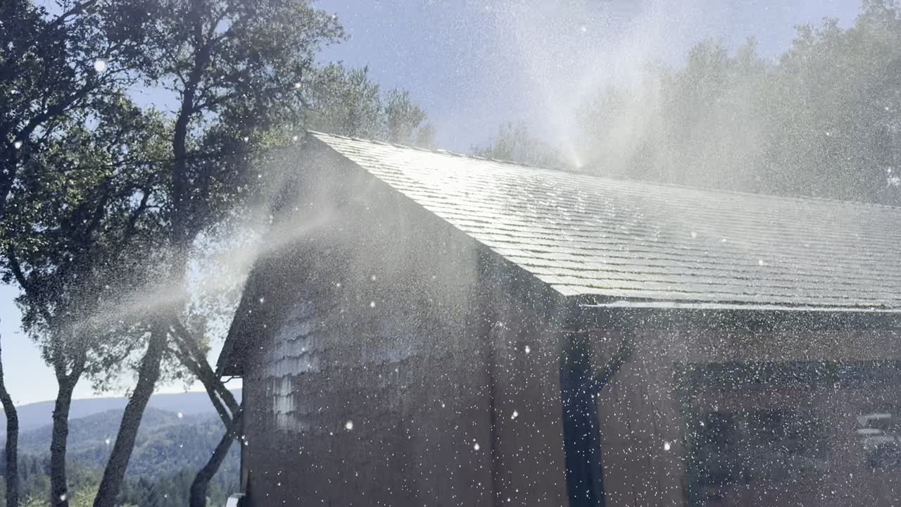 Roof and eave wildfire sprinklers soaking a home during a live coverage test